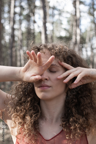Young brunette woman with closed eyes and hands on the face photo