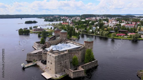 Rotating Aerial Drone Shot of Medieval Castle Olavinlinna (Finland) on a Summer Day, Savonlinna City on the Backgound photo