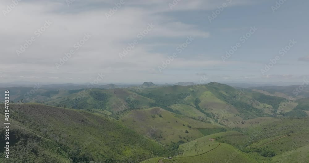 Slow aerial flying forward over green hills in partly cloudy day Slow aerial flying forward over green hills in partly cloudy day