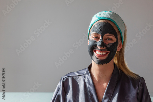 Smiling woman with charcoal mask and blue headband photo