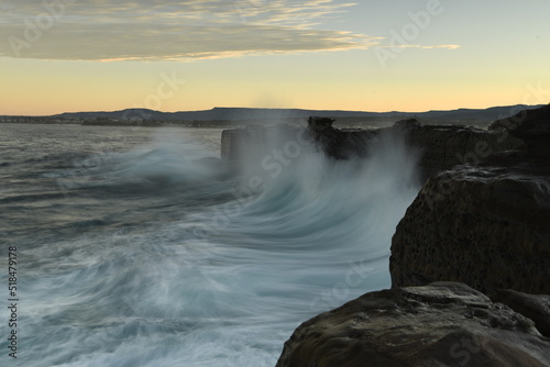 Long exposure photo of a rock wall hit by large waves, Australia