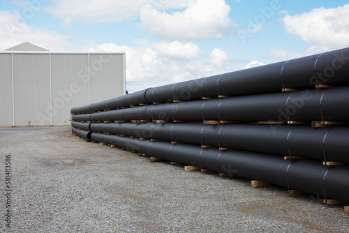 Stacks of polymer pipes and tubes outside of manufacturing facility