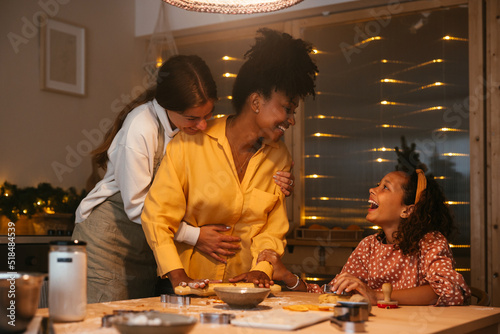 Lesbian couple with their daughter preparing Christmas cookies photo