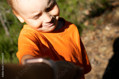 a small child takes his mother's hand and smiles. Summer walk