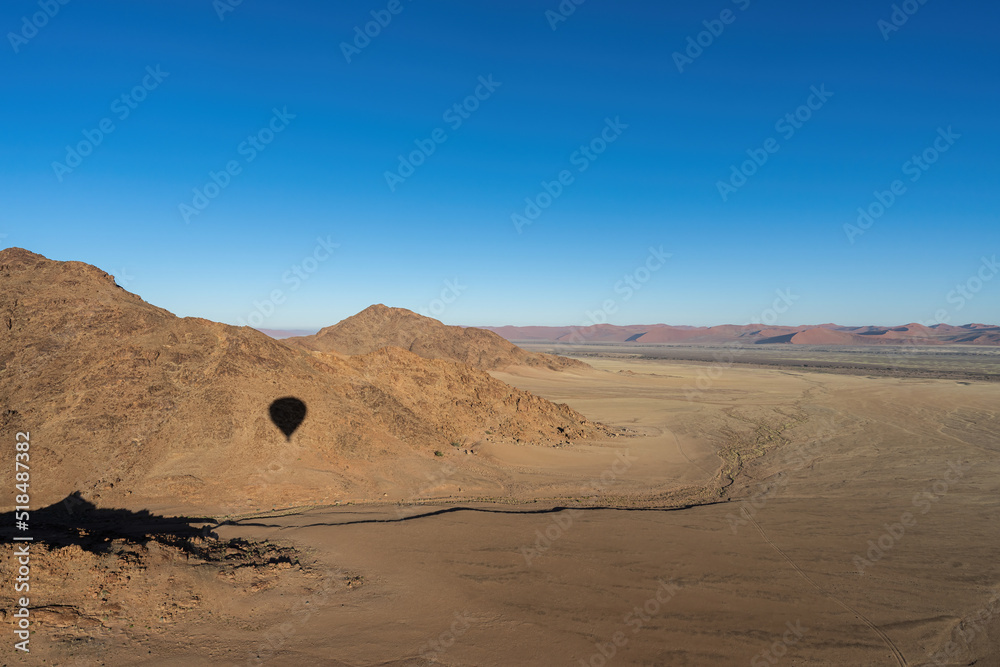 A shadow of a hot air balloon on a mountain/hill 
in the Namib Desert.