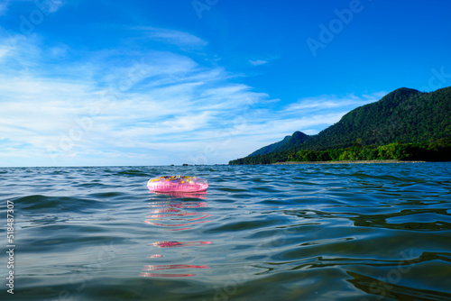 Pink inflatable ring floating in sea water near a beach photo