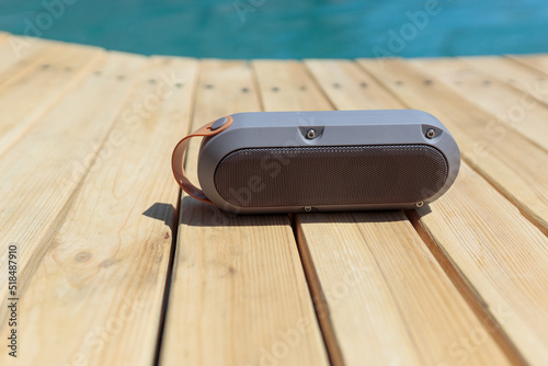 Modern portable music speaker with voice assistant near the swimming pool photo