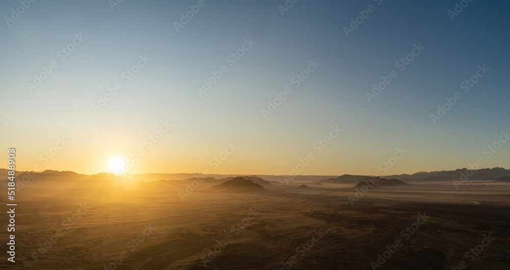 Sunrise seen from a hot air balloon during a ride in 
Sossusvlei, Namibia. Sunrays spilling over the Hills and Mountains of the Namib-Desert.