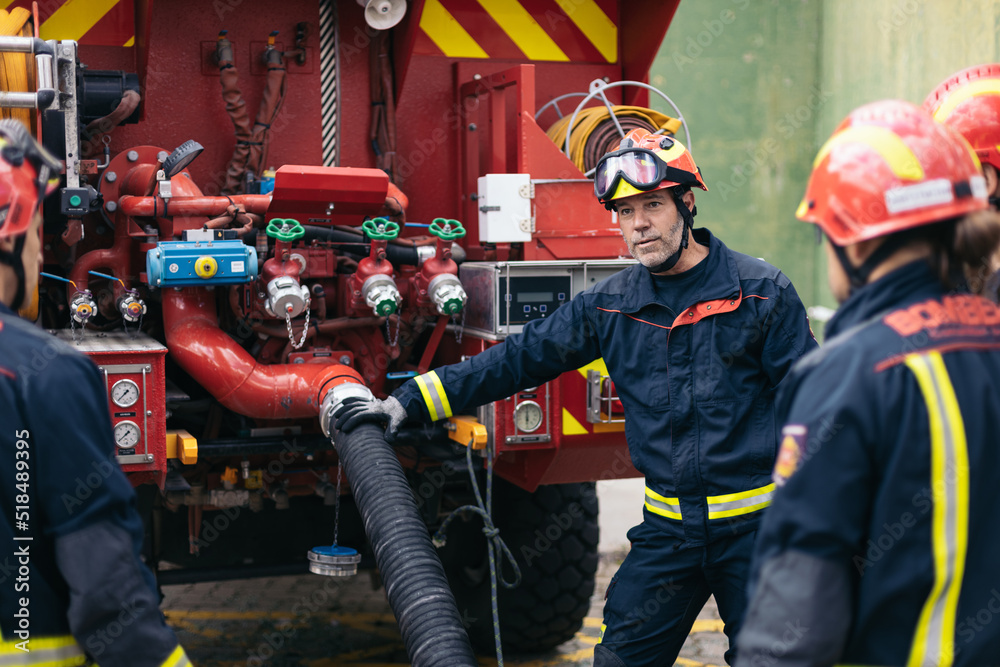 Firefighters connecting the hose to the fire truck Stock Photo | Adobe ...