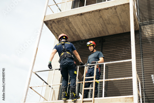 Firefighters climbing a building with a harness and ladder photo