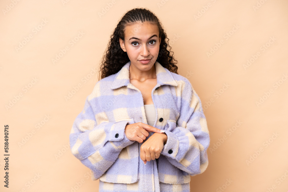 Young woman isolated on beige background making the gesture of being late Young woman isolated on beige background making the gesture of being late