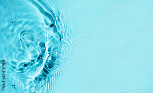 Water waves in sunlight background. Blue liquid colored clear water surface texture with splashes bubbles. 