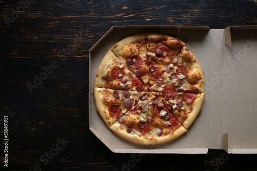 Pizza in a cardboard box against a dark background. View from above. Pizza delivery.