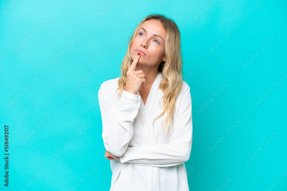Young Russian woman isolated on blue background having doubts while looking up Young Russian woman isolated on blue background having doubts while looking up