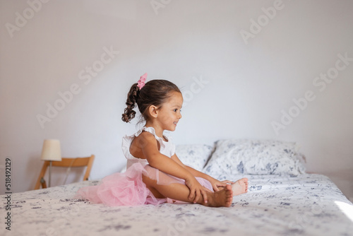 little girl dressed as a ballerina in a pink tutu at home