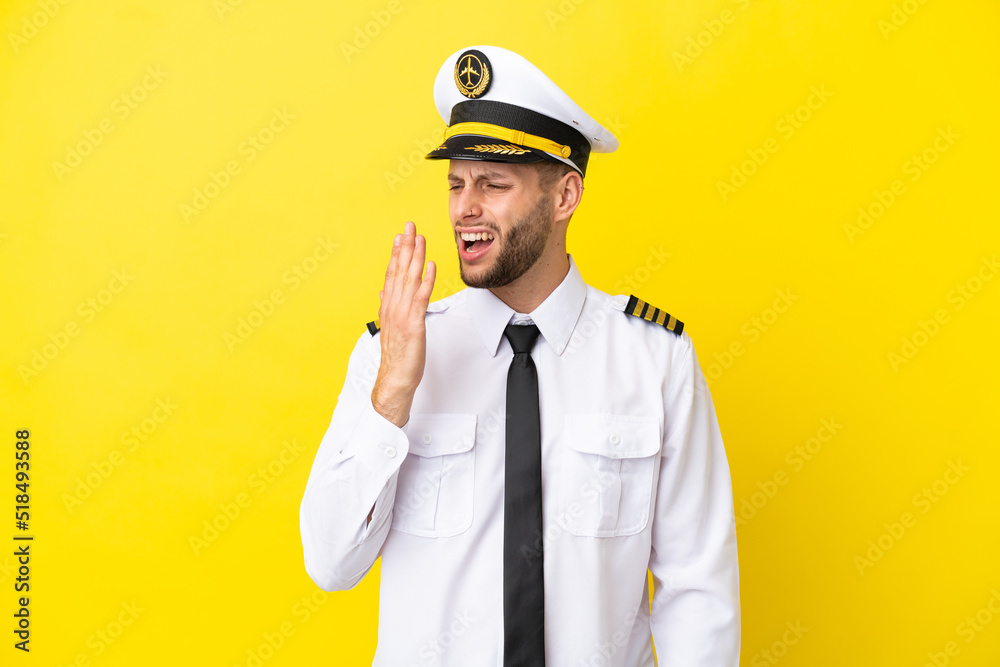 Airplane caucasian pilot isolated on yellow background yawning and covering wide open mouth with hand