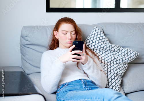 Ginger female teen with facial paralysis texting on cellphone