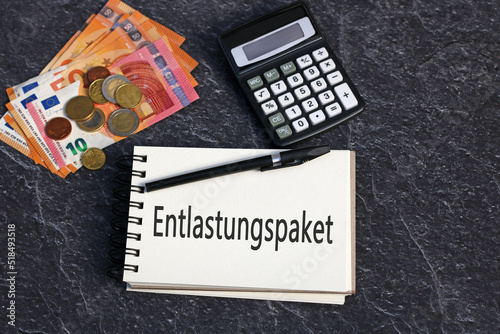 Das Wort Entlastungspaket mit Euro Geldscheinen und Taschenrechner. photo