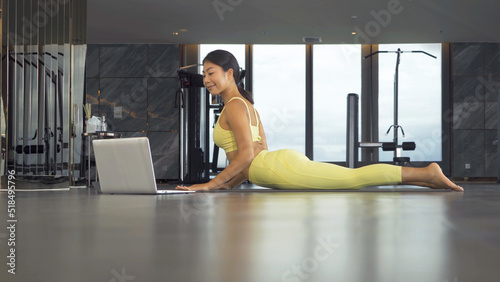 An Asian woman in yoga class club doing exercise and yoga at fitness center or gym. Indoor in sport and recreation concept. People lifestyle activity with urban city view.