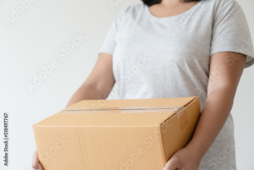 Woman carrying cardboard box to delivery parcel. Shipping parcel concept with pack and taping box. © StockerThings