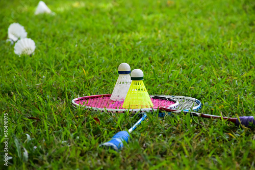 Badminton outdoors equipments; white and yellow plastic shuttlecocks and badminton rackets, on grasslawn, soft and selective focus on shuttlecocks, outdoor badminton playing concept. photo