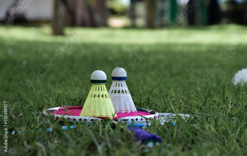 Badminton outdoors equipments; white and yellow plastic shuttlecocks and badminton rackets, on grasslawn, soft and selective focus on shuttlecocks, outdoor badminton playing concept. photo