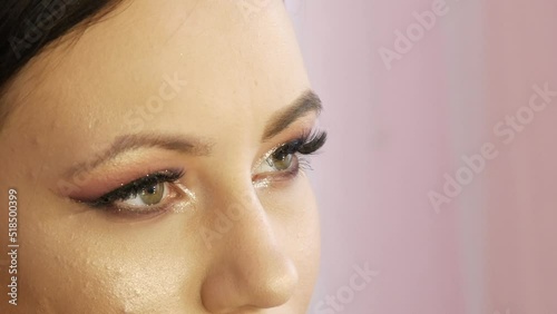 A professional make-up artist applies shiny bodily eyeshadow with a special brush in a make-up studio photo