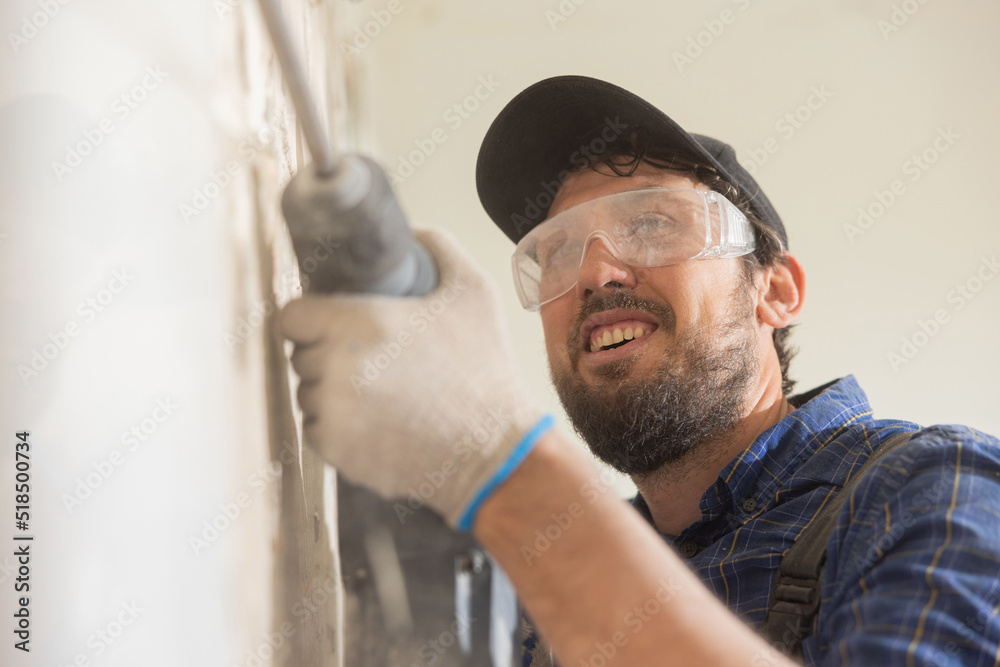 Close up portrait of a man renovating an apartment a guy wearing safety glasses is cupping tiles in the kitchen bathroom with a hammer. Close up portrait of a man renovating an apartment a guy wearing safety glasses is cupping tiles in the kitchen bathroom with a hammer.