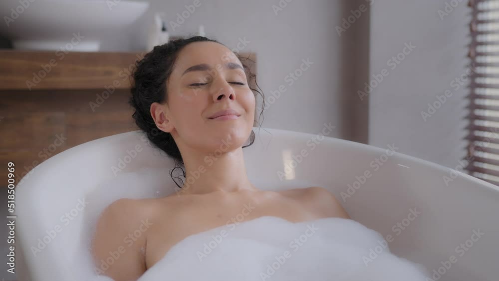 Calm relaxed woman lies in foam bath with eyes closed enjoying relaxing luxurious holiday in bathroom happy girl rests meditates thinks dreams feeling restoration concept of daily hygiene procedure Calm relaxed woman lies in foam bath with eyes closed enjoying relaxing luxurious holiday in bathroom happy girl rests meditates thinks dreams feeling restoration concept of daily hygiene procedure