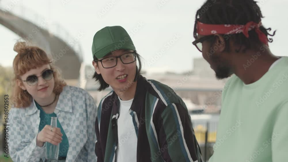 Waist up slowmo of three young multiethnic gen z hipster friends in vintage old school outfits chatting outdoors in summer Waist up slowmo of three young multiethnic gen z hipster friends in vintage old school outfits chatting outdoors in summer