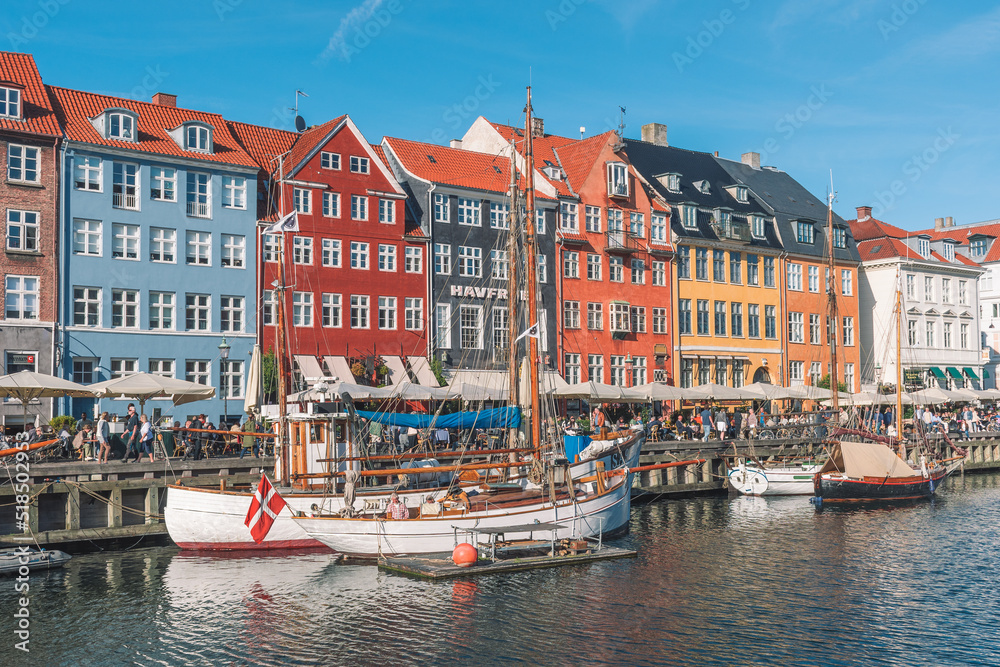 Beautiful view with colorful facade of traditional houses and old wooden ships, cruise boats along the Nyhavn Canal or New Harbour, canal and entertainment district