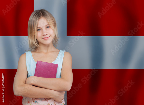 Young blonde danish girl with book against Danish flag background. Education and school in Denmark concept
