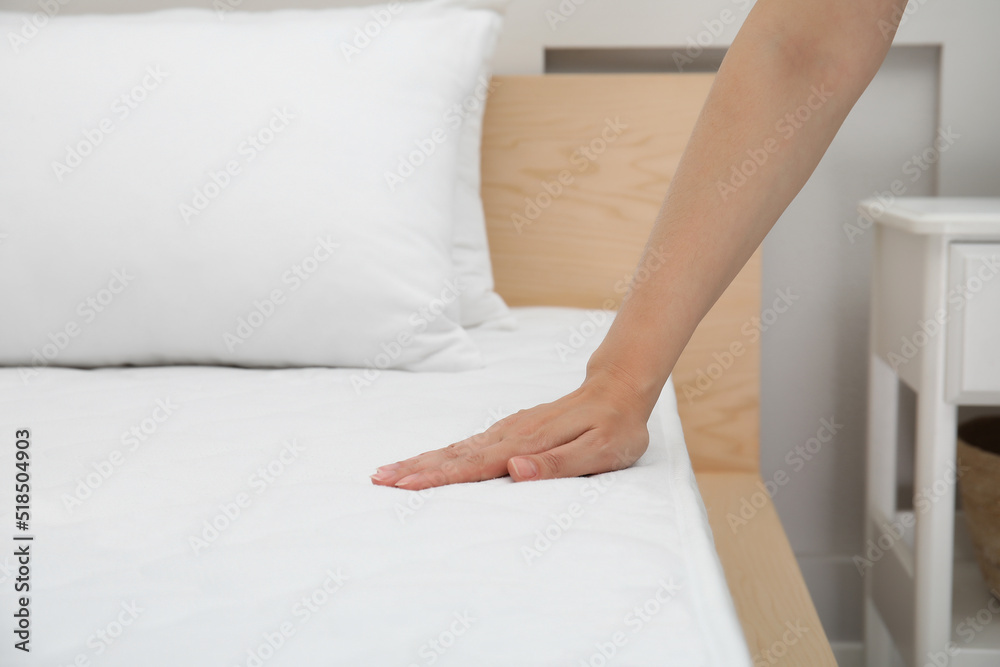 Woman touching soft white mattress on bed indoors, closeup Woman touching soft white mattress on bed indoors, closeup