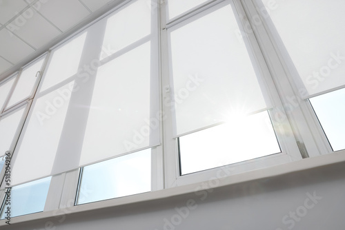 Large window with white roller blinds indoors  low angle view