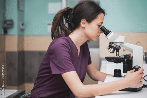 Young woman working as a veterinarian, veterinarian during the visit. Animal doctor visiting sick pets in clinic and looking microscope. People, employment, profession and animal care