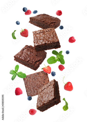 Slices of delicious chocolate brownie with fresh berries and mint flying on white background photo