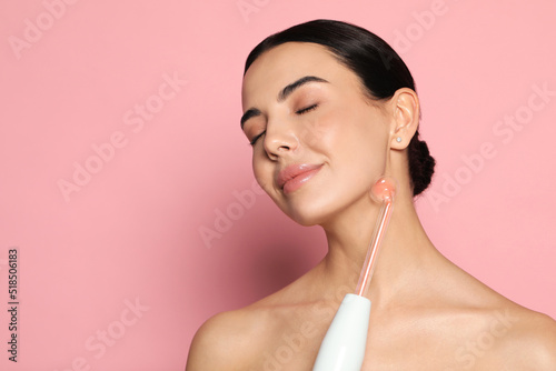 Woman using high frequency darsonval device on pink background. Space for text photo