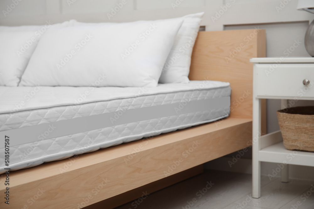Wooden bed with soft white mattress and pillows indoors Wooden bed with soft white mattress and pillows indoors