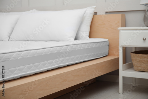 Wooden bed with soft white mattress and pillows indoors