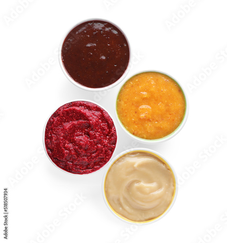 Different fruit and berry puree in bowls on white background, top view