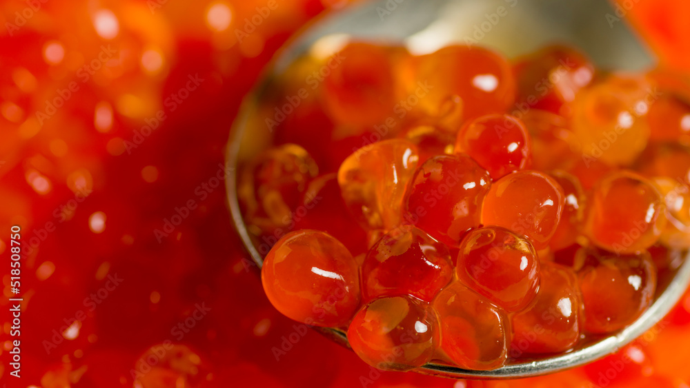 Teaspoon with juicy red caviar on background of caviar. Salmon caviar grainy. Close up. Teaspoon with juicy red caviar on background of caviar. Salmon caviar grainy. Close up.