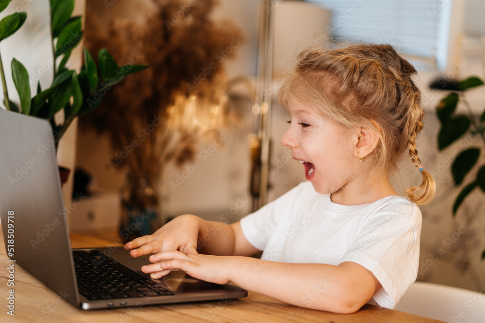 a little girl is sitting at a table with a laptop, raising her hands in the air, smiling and happy, experiencing happiness a little girl is sitting at a table with a laptop, raising her hands in the air, smiling and happy, experiencing happiness
