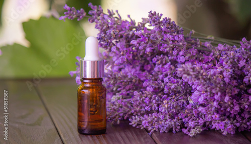 Essential oil of lavender, on a wooden background.