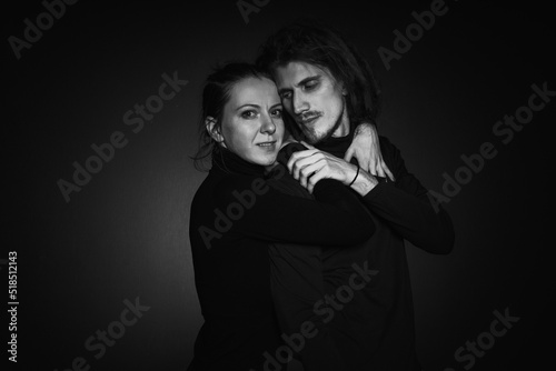Love story concept. Portrait of a beautiful couple in love posing at studio over dark background. Monochrome portrait of a passionate couple making funny grimace on face laughing playful © oleg_ermak