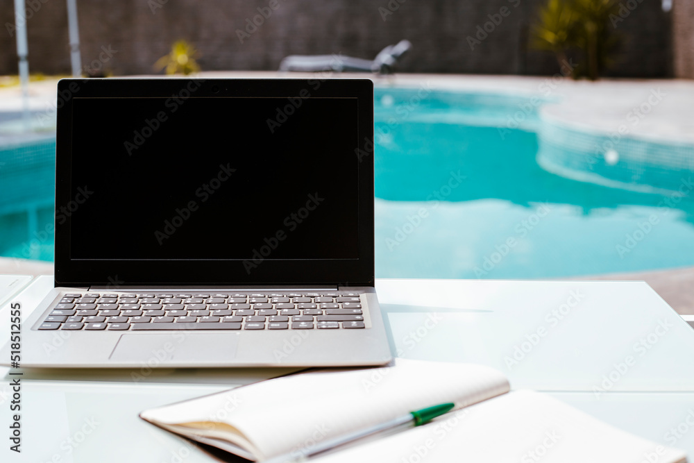 Fototapeta premium laptop with black screen, working from the pool, summer office