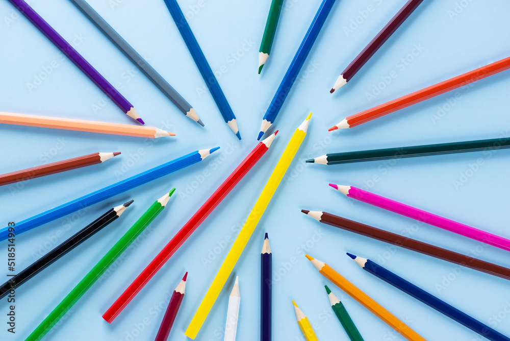 Scattered colored pencils on a blue background. Back to school concept.