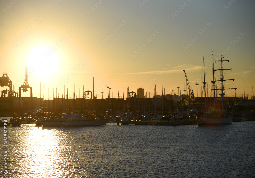 Yachts and boats in silhouette of sunset in Marina. Sunset at port. Skiff and Sailboat in harbour. Luxury yacht and fishing motor boat in yacht club at Mediterranean Sea. Yacht in sunrise in Harbor.