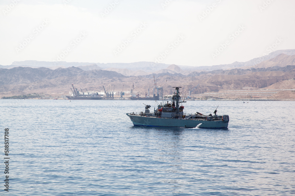 A military boat passes through the Red Sea in Eilat. Against the background of the boat, a pear port and hilly mountains are visible. Boat with echolocation systems on board. duty warship