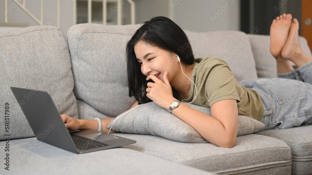 Pretty young asian woman in casual clothes lying on sofa and video call on laptop computer Pretty young asian woman in casual clothes lying on sofa and video call on laptop computer