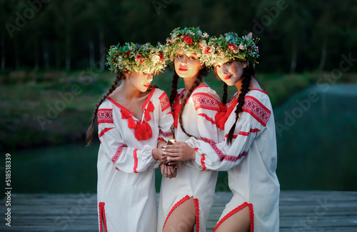 Young pagan girls with a lantern in their hands near the lake in the evening. Celebration of summer Kupala